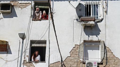 Vecinos de la calle Perdiz asomados a sus ventanas presenciando la retirada del cadáver