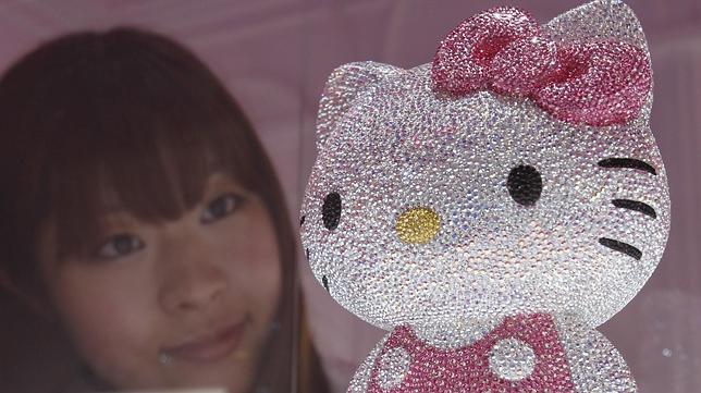 Una joven observa una figura de Hello Kitty 