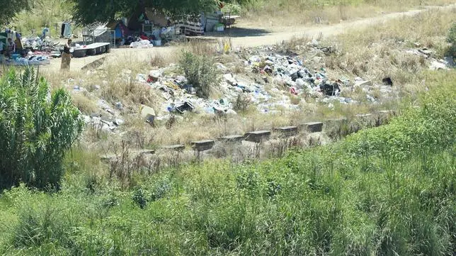 Vista del asentamiento con montones de basura junto al cauce del ro