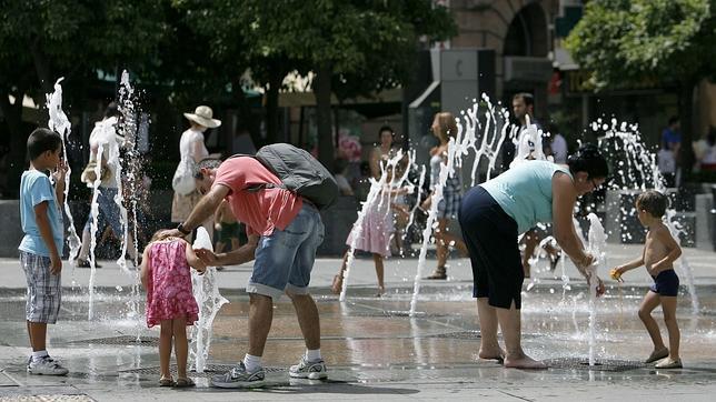 Unos padres refrescan a sus hijos en los chorros de agua de la plaza de las Tendillas