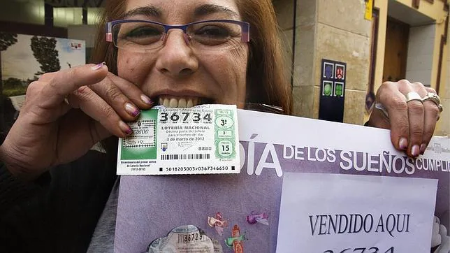 Tatiana Mejas muestra un dcimo premiado a la puerta de su administracin de lotera