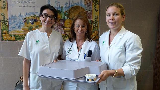 Tres integrantes del equipo de cocina con una bandeja de comida con el refrescante postre