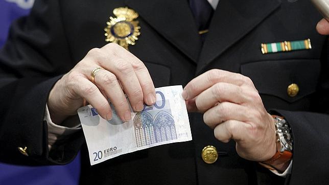 Un policía, detectando un billete de euro falso