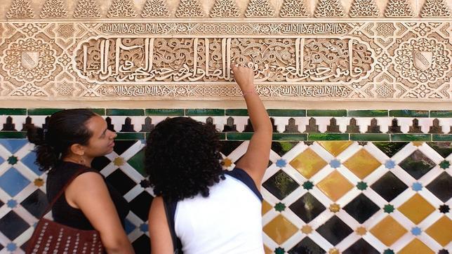 Dos turistas contemplan un fragmento del Cor�n grabado en uno de los frisos de La Alhambra
