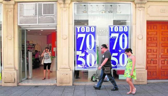 Gente paseando por la c�ntrica calle Jos� Cruz Conde, una de las v�as m�s comerciales de la ciudad. Arriba, una mujer compara precios en una tienda de ropa