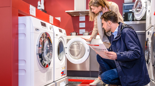 Young couple choosing washing machine in household appliance section at hypermarket