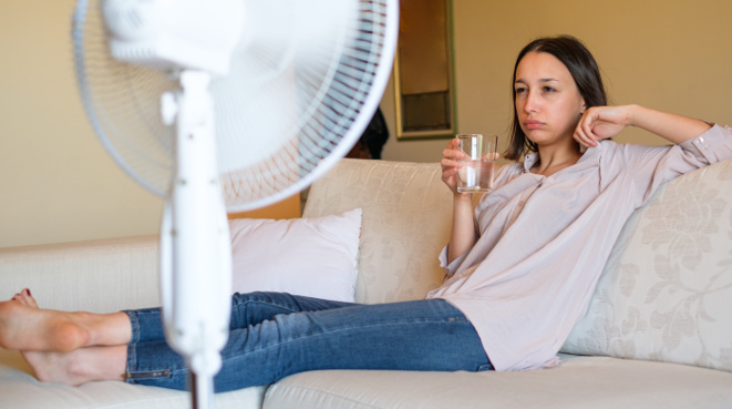 Young woman relaxing under the air fan at home