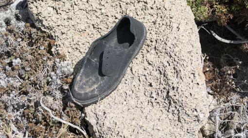 Un zapato de goma abandonado cerca del mar
