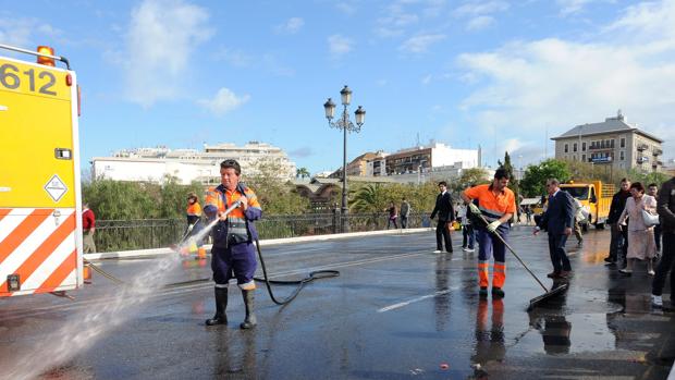Operarios de Lipasam limpiando en el puente de Triana tras el paso de cofradías