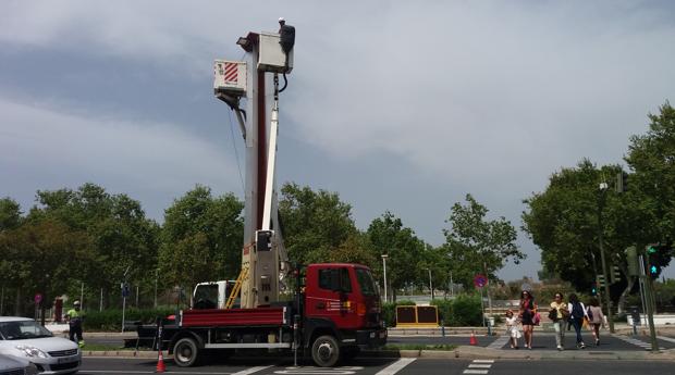 Operarios cambian los proyectores de una de las columnas de luz de la avenida Torneo
